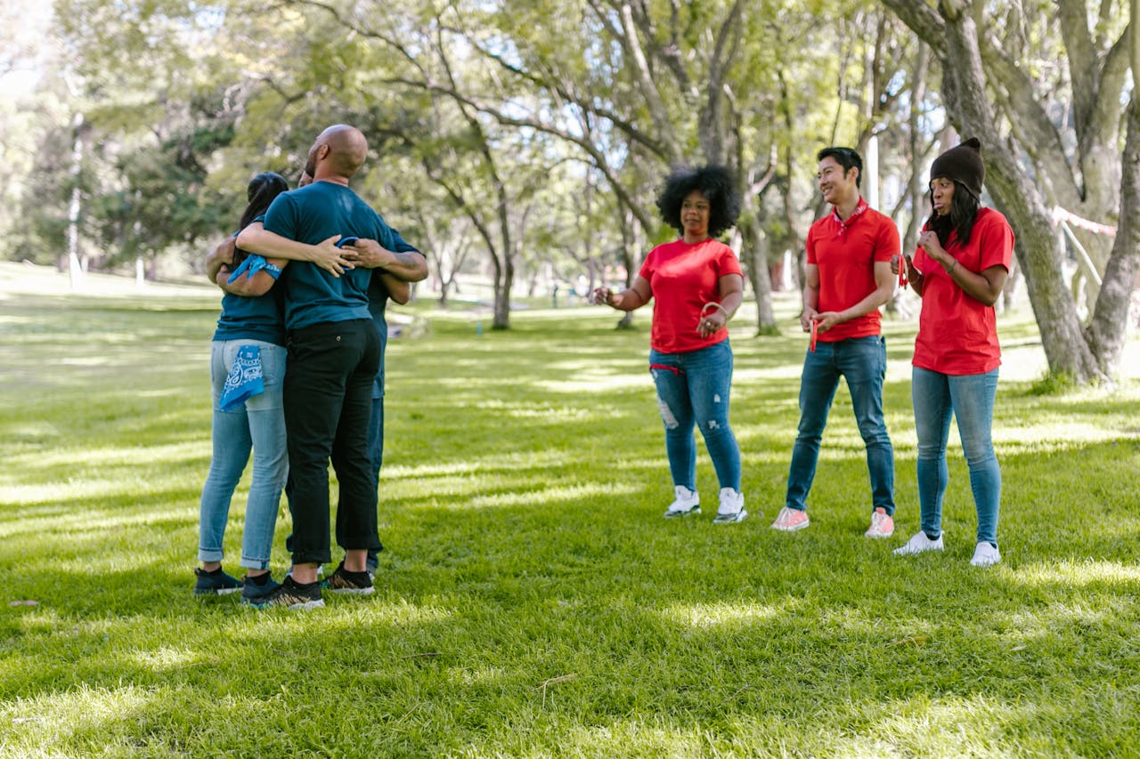 A group of adults participate in a fun outdoor team building exercise in a park setting.